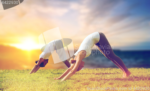 Image of smiling couple making yoga dog pose outdoors