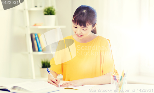 Image of happy asian young woman student learning at home