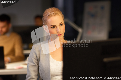 Image of businesswoman at computer working at night office