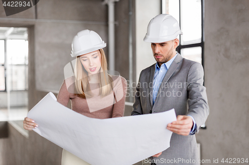 Image of architects with blueprint and helmets at office