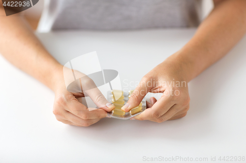 Image of woman hands opening pack of medicine capsules