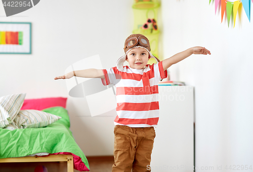 Image of happy little boy in pilot hat playing at home