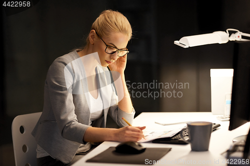 Image of businesswoman with papers working at night office