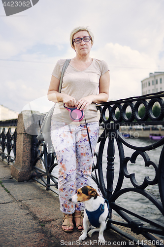 Image of Aged woman with dog on embankment