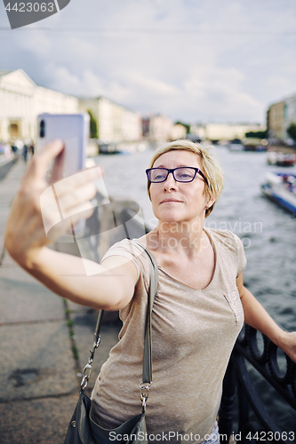 Image of Senior female taking selfie on embankment