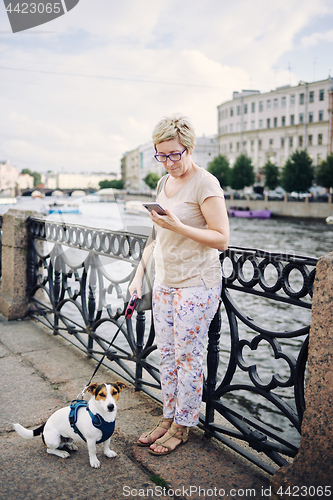 Image of Aged woman with dog on embankment