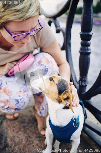 Image of Senior woman petting dog on embankment