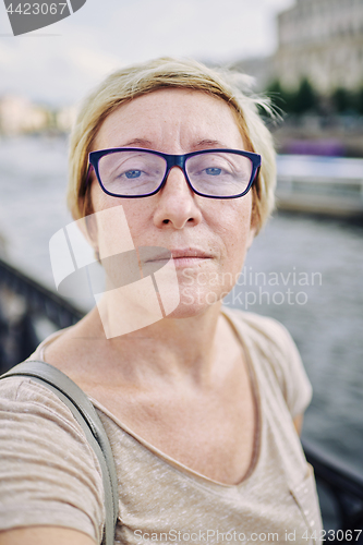 Image of Aged woman taking selfie near river