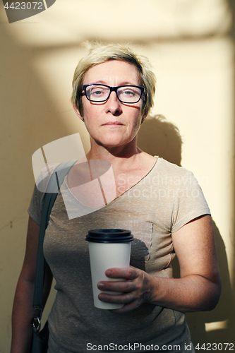 Image of Senior woman with beverage looking at camera