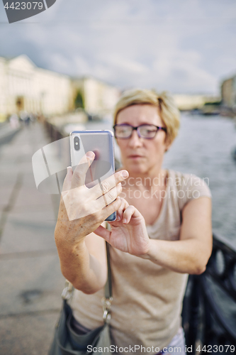 Image of Senior female taking selfie on embankment