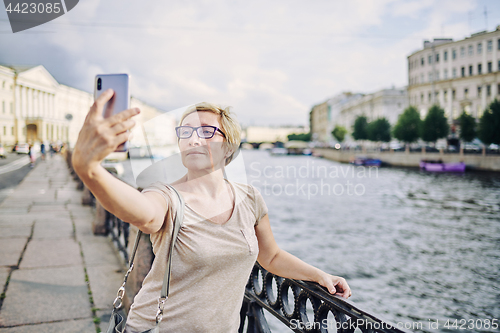 Image of Senior female taking selfie on embankment