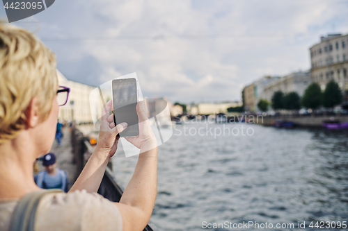 Image of Anonymous woman taking picture on embankment