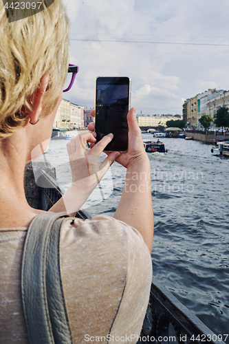 Image of Anonymous woman taking picture on embankment