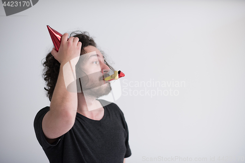 Image of Portrait of a man in party hat blowing in whistle