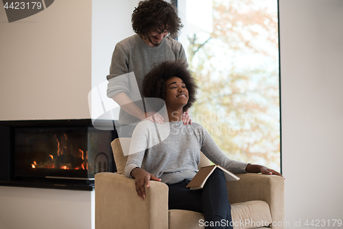 Image of multiethnic couple hugging in front of fireplace