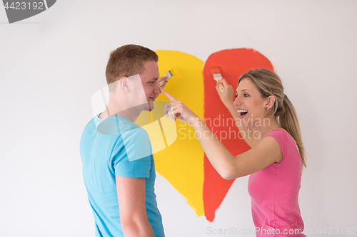 Image of couple are painting a heart on the wall