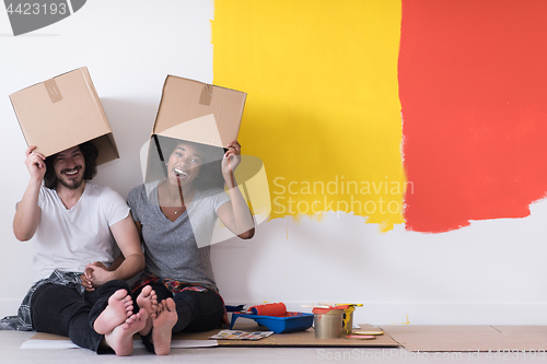 Image of young multiethnic couple playing with cardboard boxes