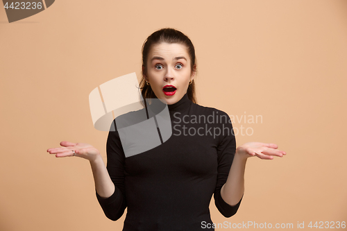 Image of Beautiful woman looking suprised isolated on pastel brownish beige