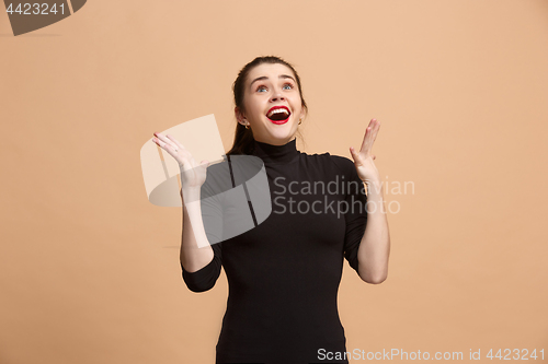 Image of Beautiful woman looking suprised isolated on pastel brownish beige