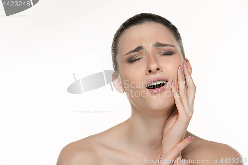 Image of Closeup portrait of young woman suffering from terrible tooth pain, touching pressing her cheek. Dental care and toothache.