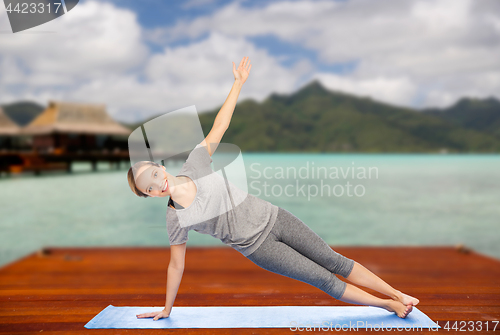 Image of woman making yoga in side plank pose outdoors