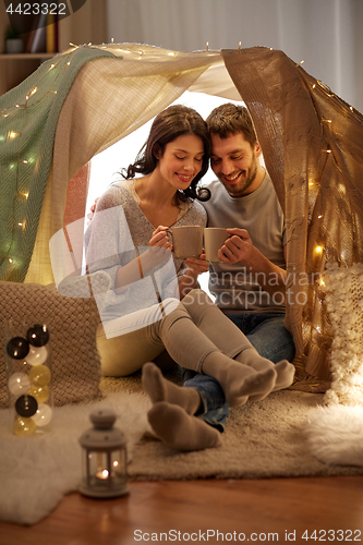 Image of couple drinking coffee or tea in kids tent at home