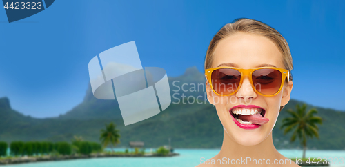 Image of woman in shades showing tongue over summer beach