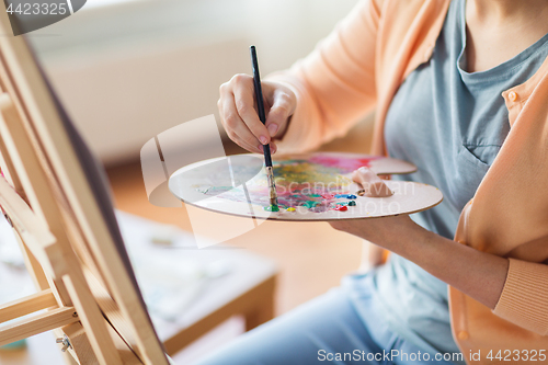 Image of artist with palette and brush painting at studio