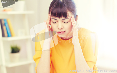 Image of tired asian woman suffering from headache at home