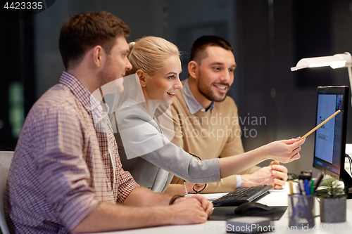 Image of business team with computer working late at office