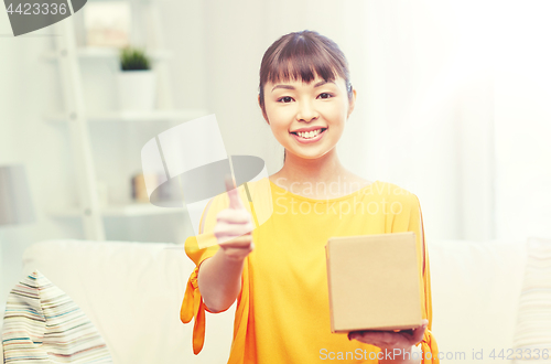 Image of happy asian young woman with parcel box at home