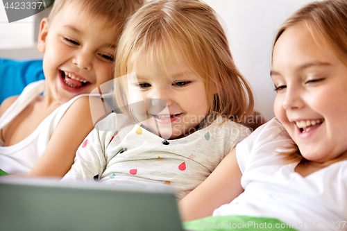 Image of happy little kids with tablet pc in bed at home