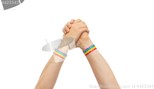 Image of hands with gay pride wristbands in winning gesture