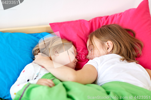 Image of happy little girls sleeping in bed at home