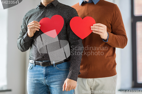 Image of close up of happy male couple holding red hearts