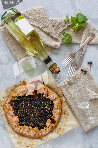Image of Berry pie (Galette), bottle of white wine and a glass.