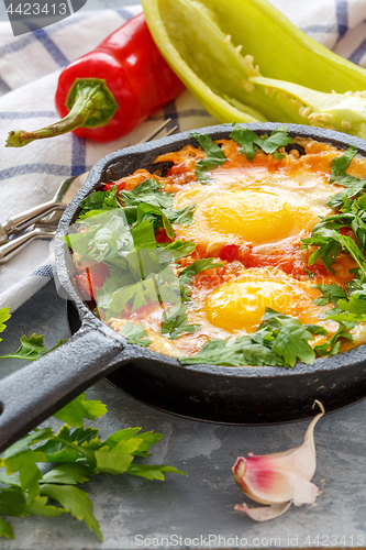 Image of Shakshuka. Frying pan with eggs in tomato sauce.