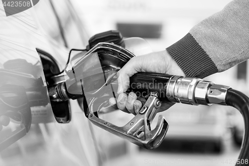 Image of Closeup of mans hand pumping gasoline fuel in car at gas station.