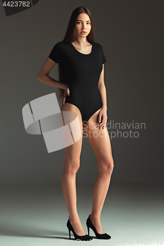 Image of Fashion woman portrait. Beautiful teen model in a black swimsuit. Studio shot, gray background.