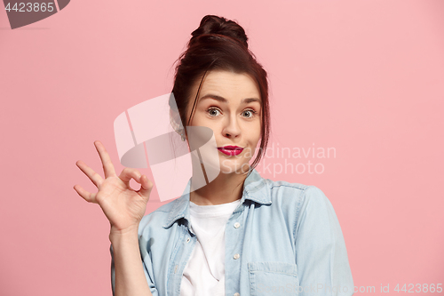 Image of The happy business woman standing and smiling against pink background.