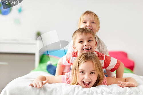 Image of happy little kids having fun in bed at home