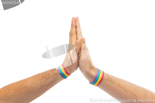 Image of hands with gay pride wristbands make high five