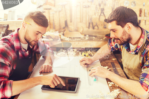 Image of workmen with tablet pc and blueprint at workshop