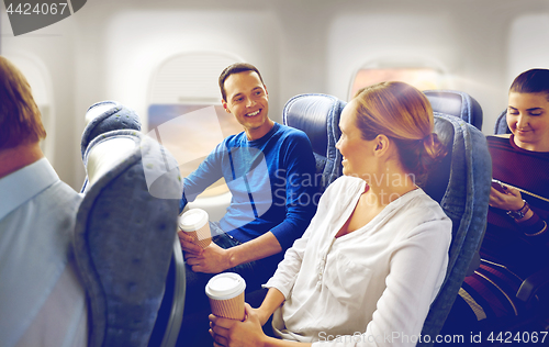 Image of happy passengers with coffee talking in plane