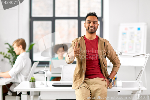 Image of smiling indian man showing thumbs up at office