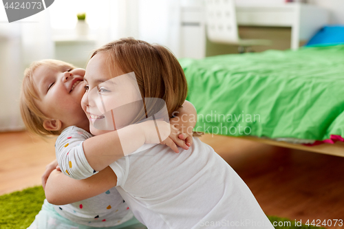 Image of happy little girls or sisters hugging at home