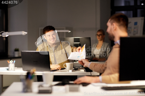 Image of coworkers with papers working at nigh office