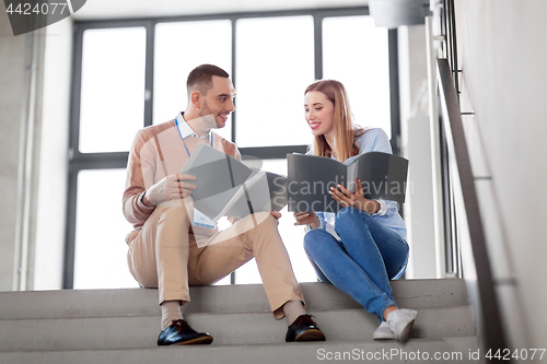 Image of man and woman with folders at office stairs