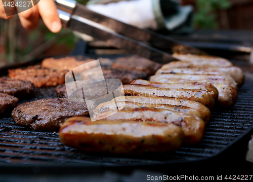 Image of Cook tends to food on a barbecue