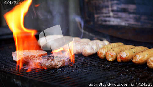 Image of Flame rises around a hamburger on a barbecue 